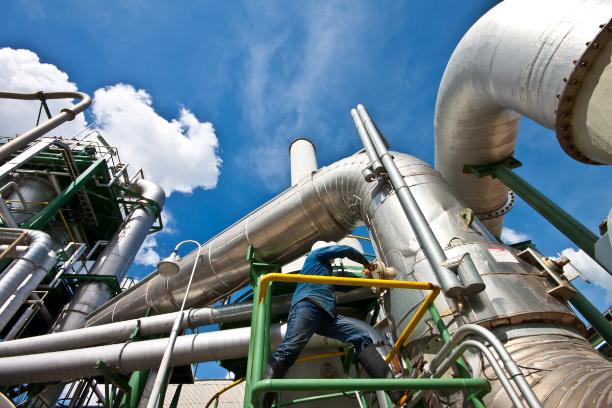 Safety engineer wearing a hard hat reviewing industrial controls.